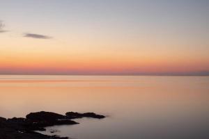 einen Sonnenuntergang über dem Wasser mit Felsen im Vordergrund in der Unterkunft Toxotis Villas in Armenistis