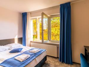 een slaapkamer met een bed met blauwe gordijnen en een raam bij Park Apartamenty Chrzanów in Chrzanów