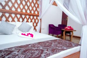 a bedroom with a bed and two purple chairs at Kuti Hotel Stone Town in Ngambo