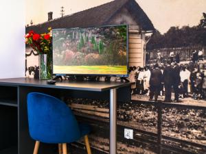 un ordinateur assis sur un bureau avec une chaise bleue dans l'établissement Park Apartamenty Chrzanów, à Chrzanów