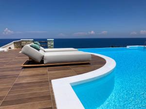 ein Pool mit einer Couch neben dem Wasser in der Unterkunft Toxotis Villas in Armenistis