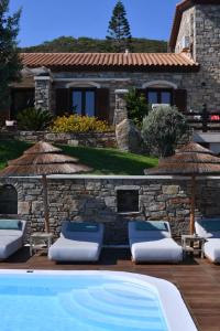 a pool with chairs and umbrellas next to a house at Toxotis Villas in Armenistis