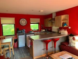a kitchen with red walls and a counter with red stools at Snowberry Cottages No1 in Onich