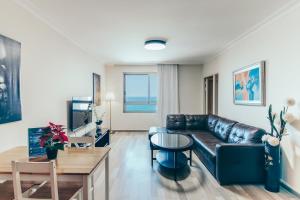 a living room with a leather couch and a table at Almog Haifa Israel Apartments מגדלי חוף הכרמל in Haifa