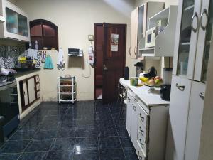 cocina con armarios blancos y suelo de baldosa negra en Casa acomodação em Araruama en Araruama