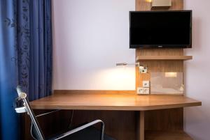 a room with a desk with a tv and a chair at Holiday Inn Express Friedrichshafen, an IHG Hotel in Friedrichshafen