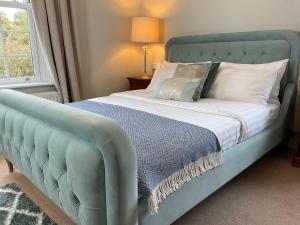 a bed with a blue headboard in a bedroom at The Broomsquire in Aldermaston