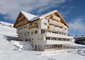 budynek w śniegu przed górą w obiekcie Noldis Hotel w mieście Serfaus