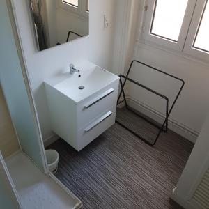 La salle de bains blanche est pourvue d'un lavabo et d'un miroir. dans l'établissement Granville Plage Plat Gousset, à Granville