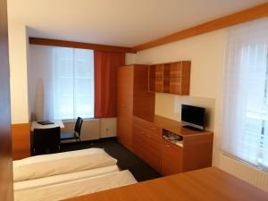 a hotel room with two beds and a desk and a television at Villa Styria in Bad Aussee