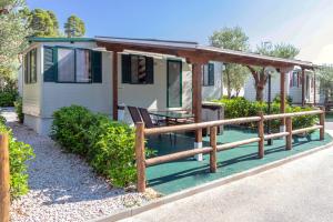 une maison avec une terrasse couverte et une clôture en bois dans l'établissement Camping Castello, à Neos Marmaras