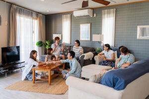 ペンション ラナカイハウス沖縄 في أونا: مجموعة من الناس يجلسون في غرفة المعيشة يلعبون
