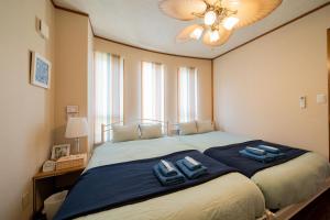 1 dormitorio con 1 cama grande y 2 toallas azules en ペンション ラナカイハウス沖縄, en Onna