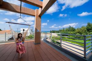 恩納的住宿－ペンション ラナカイハウス沖縄，坐在吊床上和婴儿一起的女人