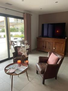 un soggiorno con 2 sedie, un tavolo e una TV di Comme à la maison près de la DOLCE VIA a Saint-Fortunat-sur-Eyrieux