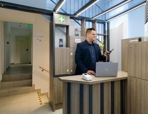 a man standing at a desk with a laptop at RES City Residence Hotel Budapest in Budapest