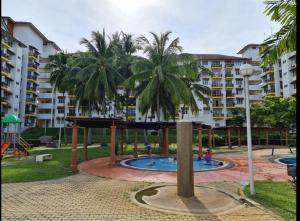 einen Spielplatz in einem Park mit Palmen und Gebäuden in der Unterkunft Laguna Condo Resort Port Dickson in Port Dickson