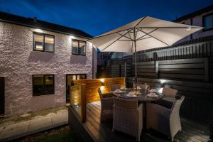 een houten terras met een tafel en een parasol bij Rockside - Luxury 1 bedroom home with hot tub central, parking pet friendly hot tub turns off 930pm in Windermere