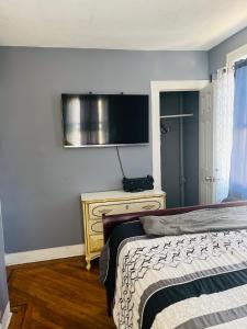 a bedroom with a bed and a television on the wall at Royalbluecozy in Saint Albans