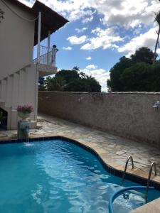 a swimming pool in front of a house with a stone wall at casa centro historico 5 quartos in Pirenópolis