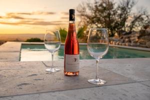 B&B Bacchus Grotto with only 1 suite 45m2 plunge pool privé في كيران: زجاجة من النبيذ وكأسين من النبيذ على الطاولة