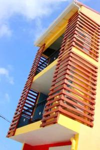 wysoki żółty budynek z balkonem w obiekcie IMMEUBLE NEBOT w mieście Grand-Bourg