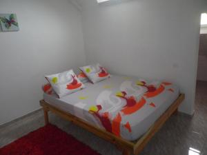 a bed with white sheets and red and white pillows at IMMEUBLE NEBOT in Grand-Bourg