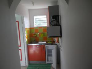 una piccola cucina con pareti arancioni e verdi di IMMEUBLE NEBOT a Grand-Bourg