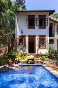 Una motocicleta en una piscina frente a una casa en Villa Rica Pousada Boutique en Brumadinho