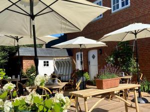 a patio with tables and umbrellas in front of a building at GUNDT Amrum in Nebel