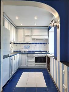 ポルタヴァにあるSea Style - Сеть апартаментов Alex Apartments Бесконтактное заселение 24-7の白いキャビネットと青いタイルのキッチン