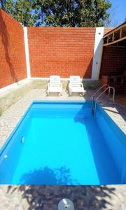 a blue swimming pool with two chairs and a brick wall at Casa de Campo Belén - Lunahuaná in Lunahuaná +16 photos
