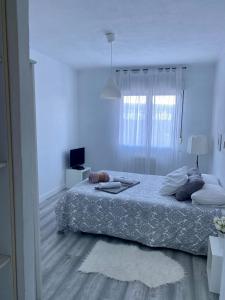 Habitación blanca con cama y ventana en 1 linea de playa poniente, puerto deportivo recien reformado, en Gijón