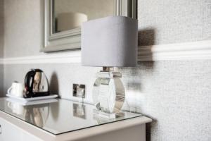 a lamp on a glass table with a mirror at Roundthorn Country House & Luxury Apartments in Penrith
