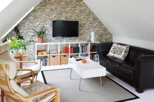 a living room with a black couch and a tv at Torsborgs Gård in Simrishamn