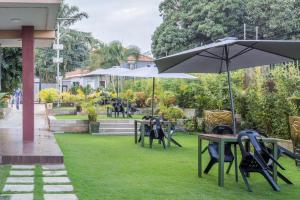 a group of tables and chairs with an umbrella at KRM Hotel - Caran in Kampala