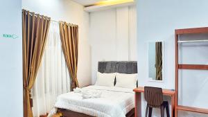 a bedroom with a bed and a desk and a window at Depik Inn in Takengon