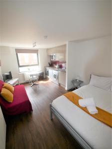 a bedroom with a large bed and a kitchen at Hill House Holiday Apartments in Bournemouth
