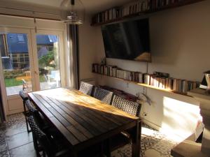 a dining room with a wooden table and a tv at Fisherman's cottage in Ile d'Arz