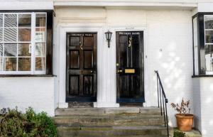 two black doors on a white house with stairs at The House with Two Front Doors in Rye