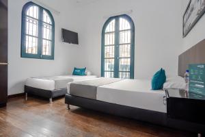 1 dormitorio con 2 camas y 2 ventanas en Ayenda La Tua Casa, en Bogotá
