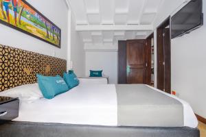a bedroom with a large white bed with blue pillows at Ayenda La Tua Casa in Bogotá