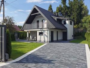 ein weißes Haus mit einem schwarzen Dach und einer Auffahrt in der Unterkunft Dream House in Gdów