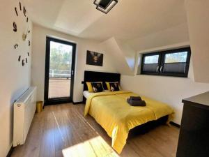 a bedroom with a bed with yellow sheets and windows at Dream House 8 osób - cały dla Ciebie in Gdów