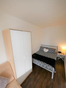a small room with a bed and a white wall at Hill House Holiday Apartments in Bournemouth