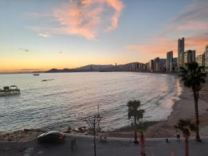 widok na plażę o zachodzie słońca z miastem w obiekcie Don Miguel 1-Fincas Benidorm w mieście Benidorm