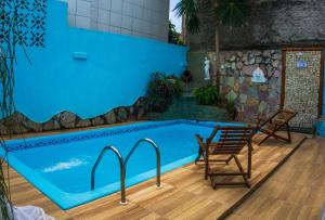 a swimming pool with two chairs next to a swimming pool at Pousada Sonho Meu in Pipa