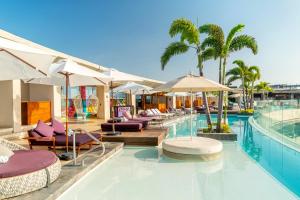 a hotel room with a pool, chairs, and umbrellas at Thompson Playa del Carmen - Adults Only - a concept by Hyatt in Playa del Carmen