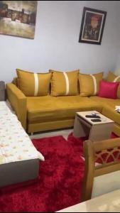 ein Wohnzimmer mit einem gelben Sofa und einem roten Teppich in der Unterkunft JANO apartment Korce in Korçë