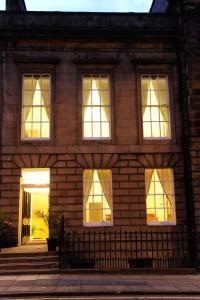a brick house with lit windows on the front at Edinburgh City Suites in Edinburgh